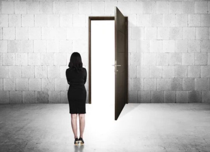 A student standing before an open, light-filled door